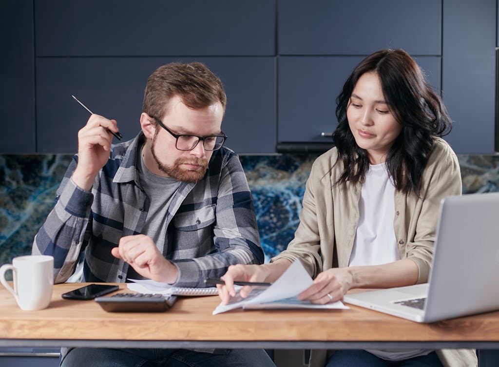 A Couple Looking at a Paper on a Desk with a Calculator