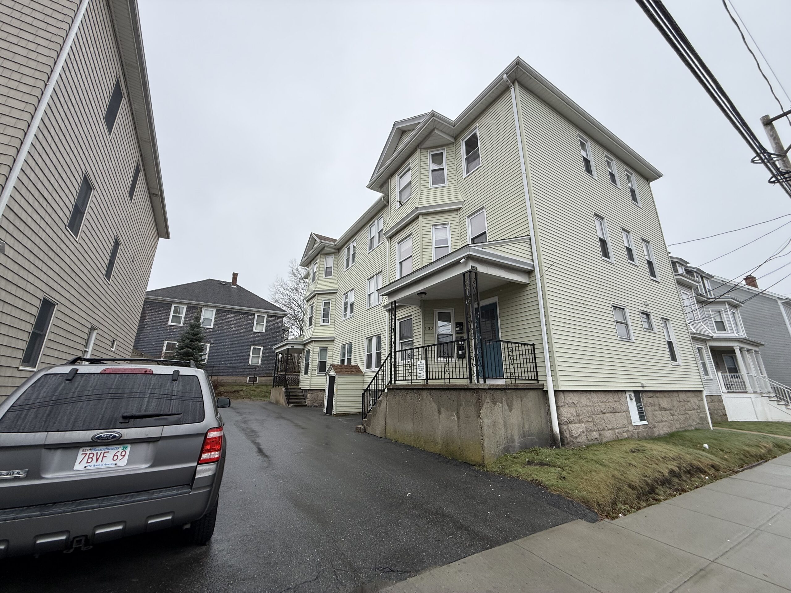 Side street view of the three-story sage-green vinyl exterior
