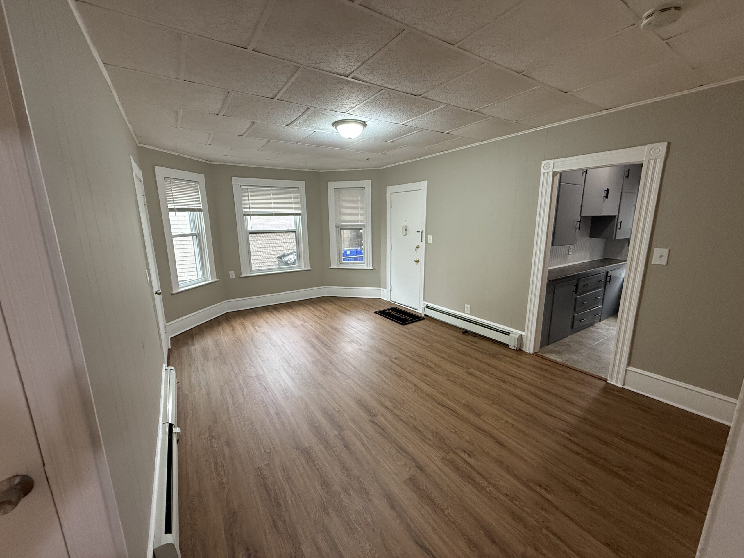 Living room with bay windows and front door at 139 Oliver Street, Fall River MA