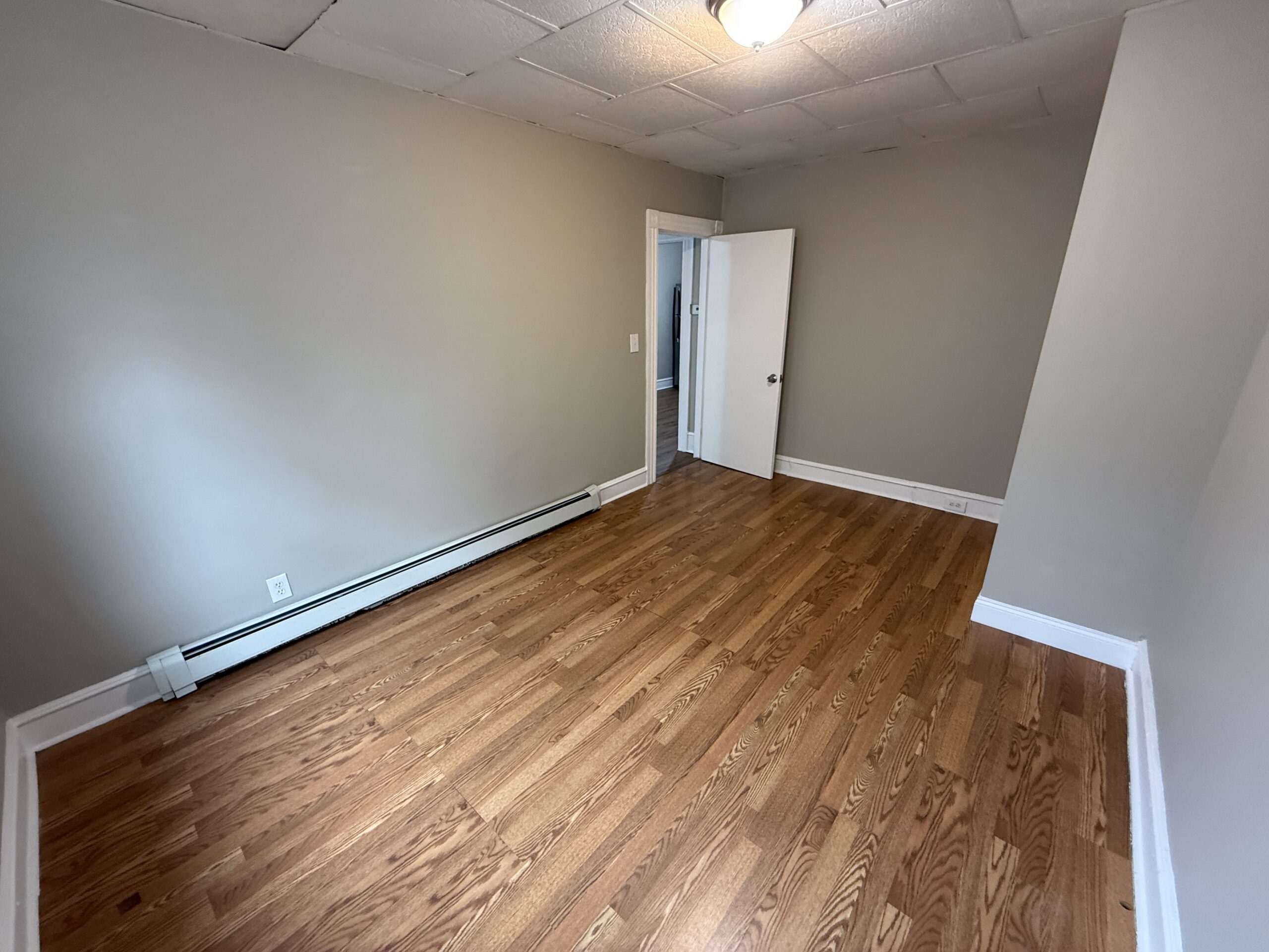 Bedroom 2 with gas baseboard heat cover and hardwood flooring