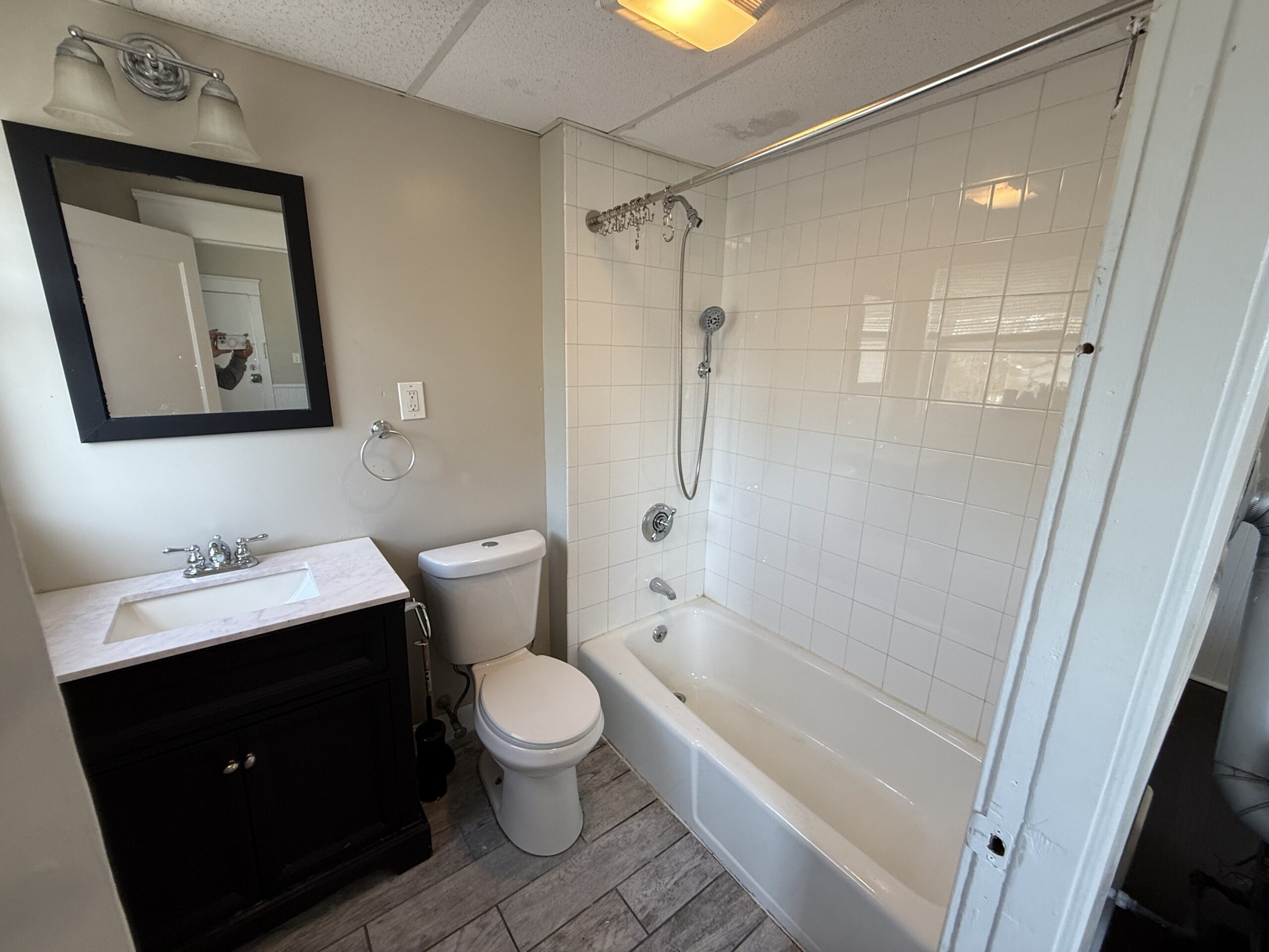 Full bathroom with white tile tub surround and dark vanity at 170 King Street, Fall River MA