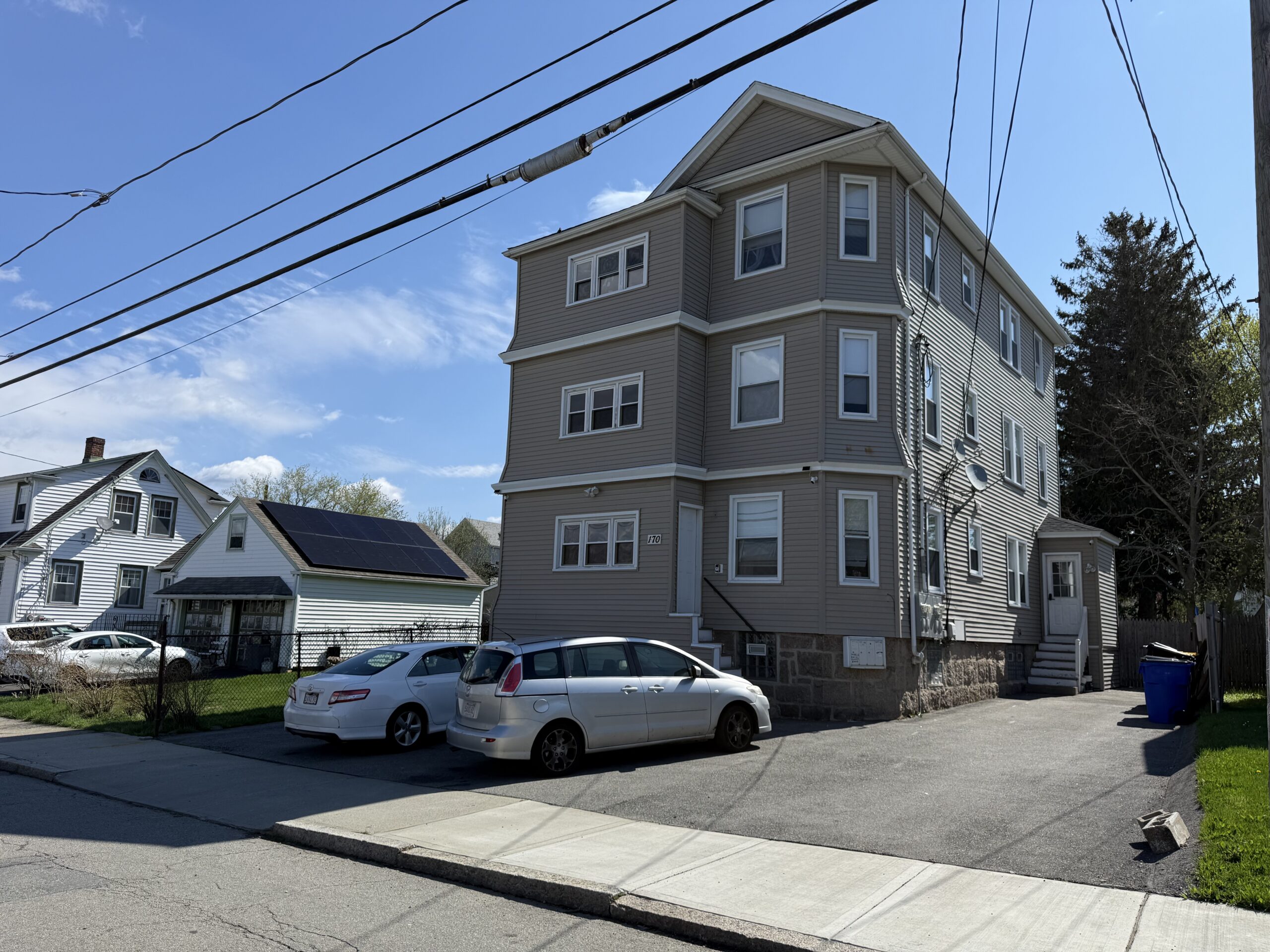 Three-family gray-vinyl building with off-street driveway at 170 King Street, Fall River MA