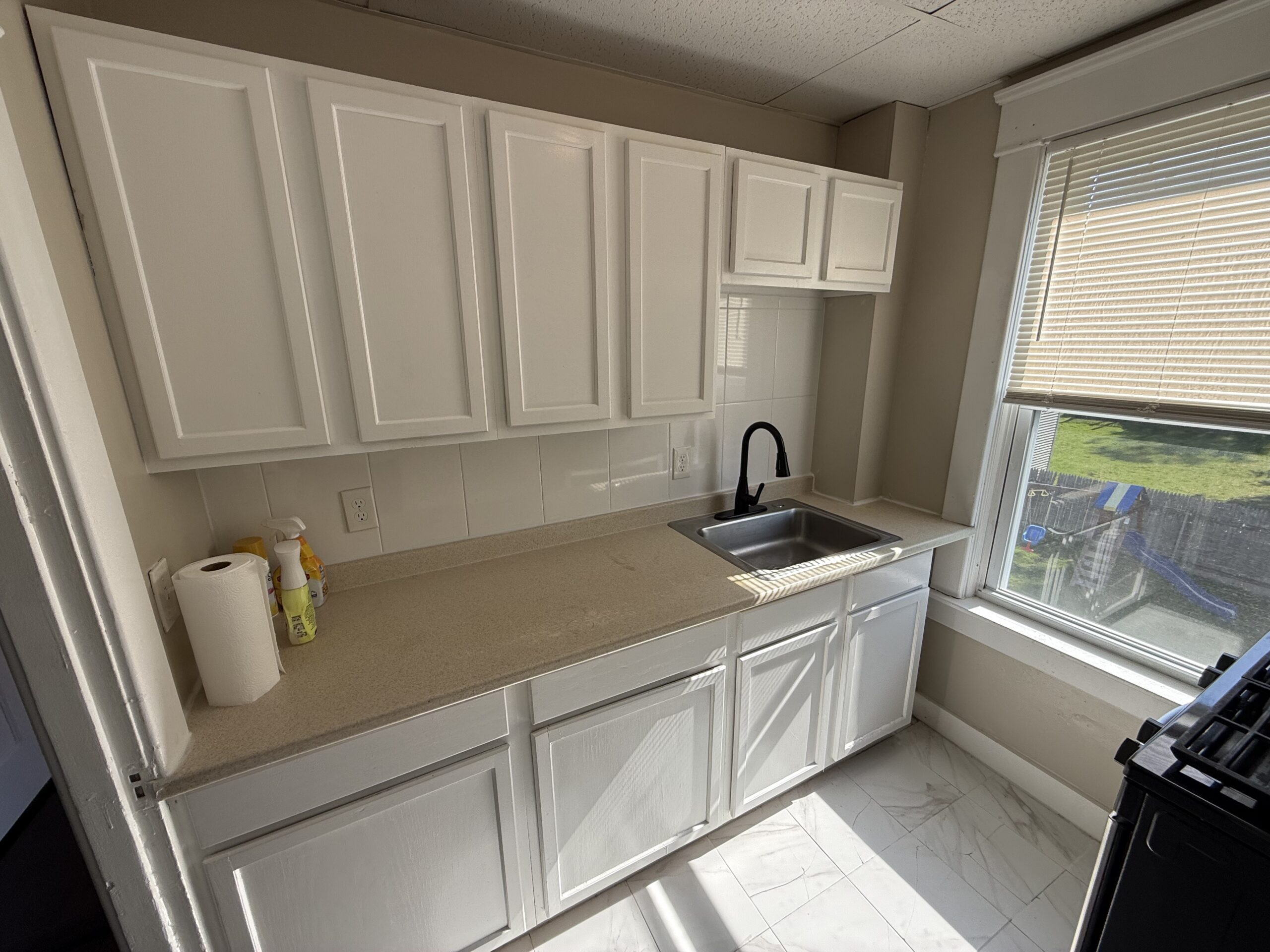 Kitchen with stainless sink, white cabinets, and large window at 170 King Street, Fall River MA