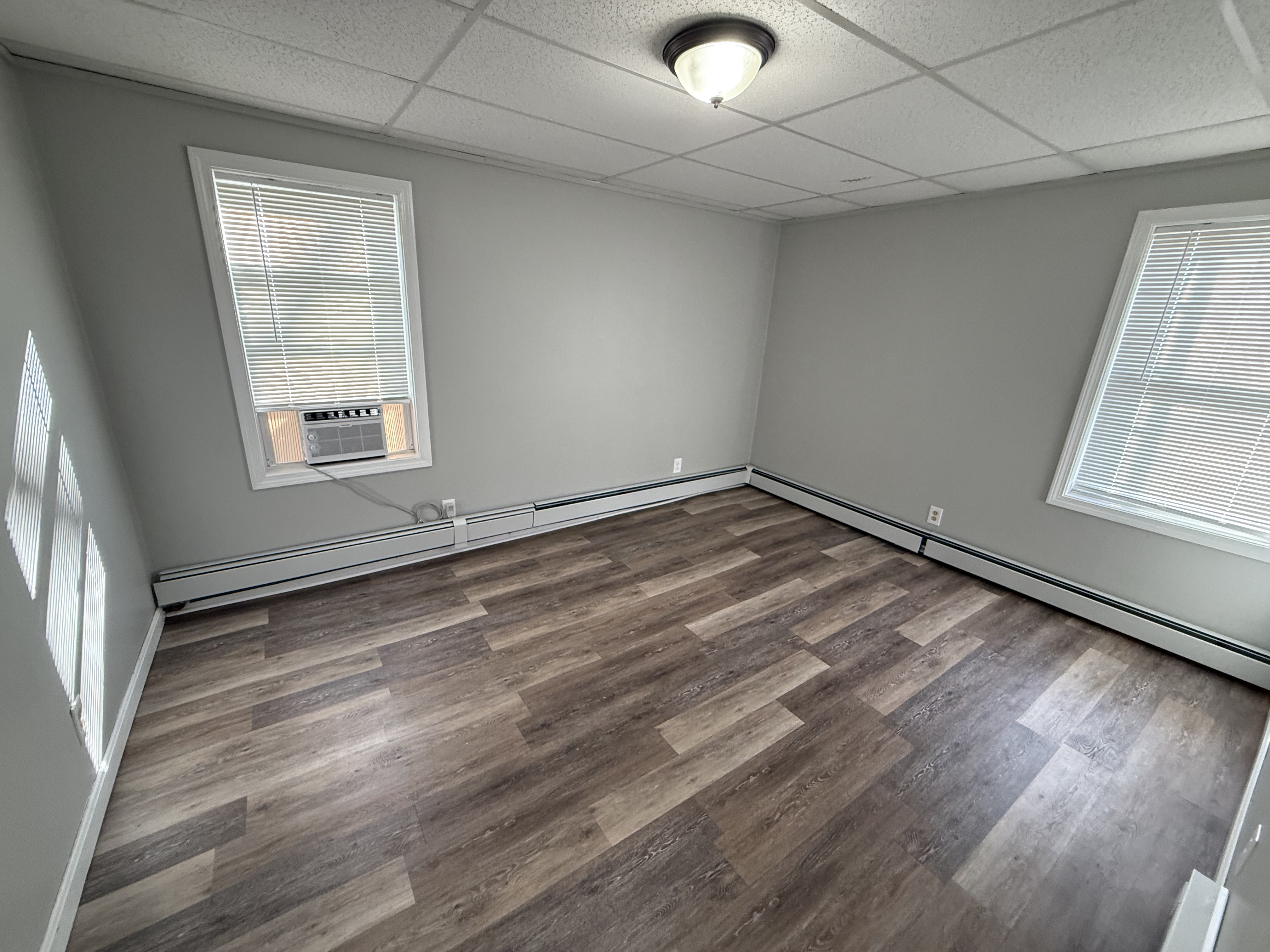 Bedroom 1 with two windows, window AC unit, and vinyl plank floors at 41 Donnelly St Apt 2