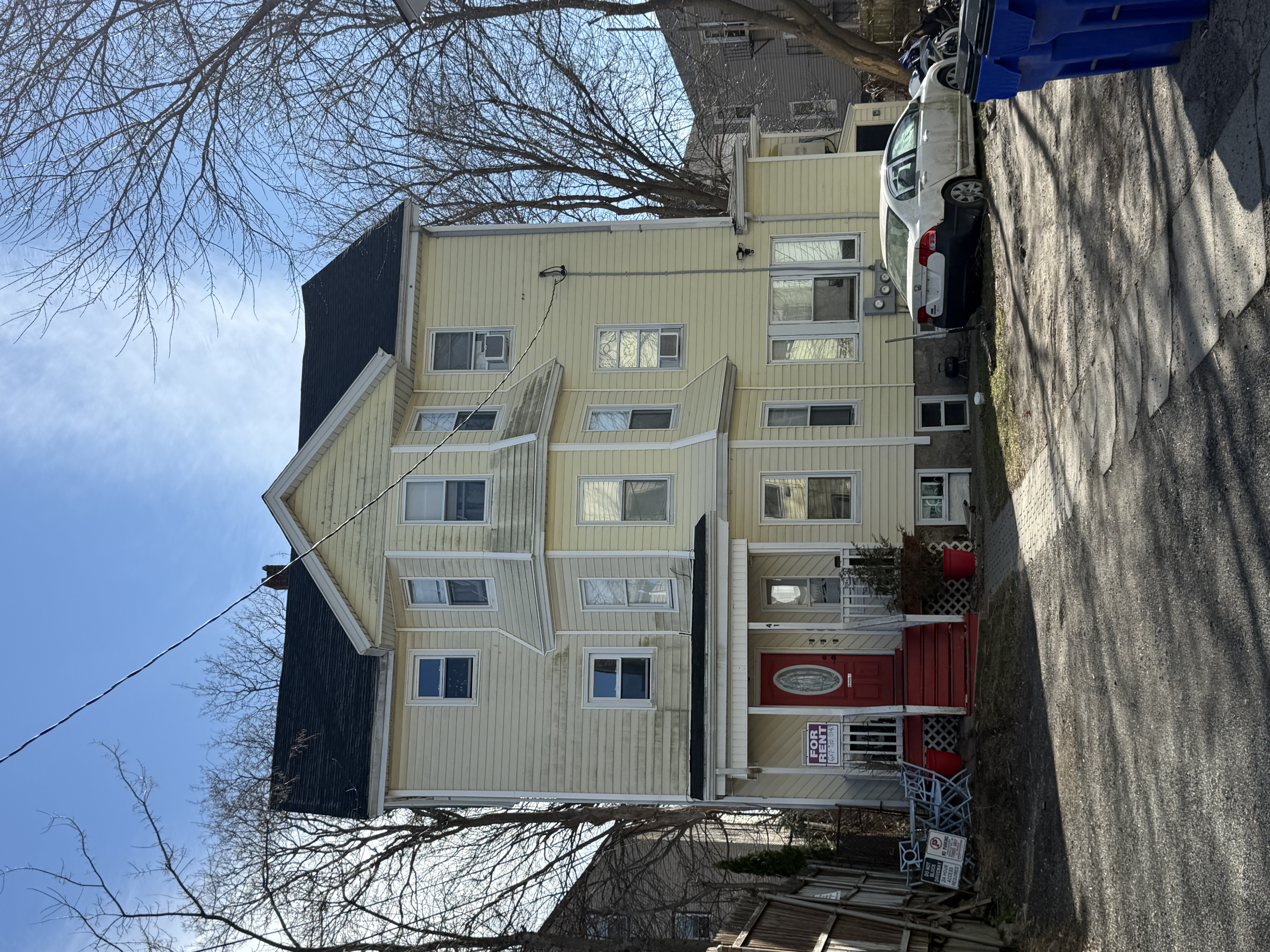 Yellow vinyl-sided Victorian three-decker exterior at 41 Donnelly St in Fall River's Flint neighborhood