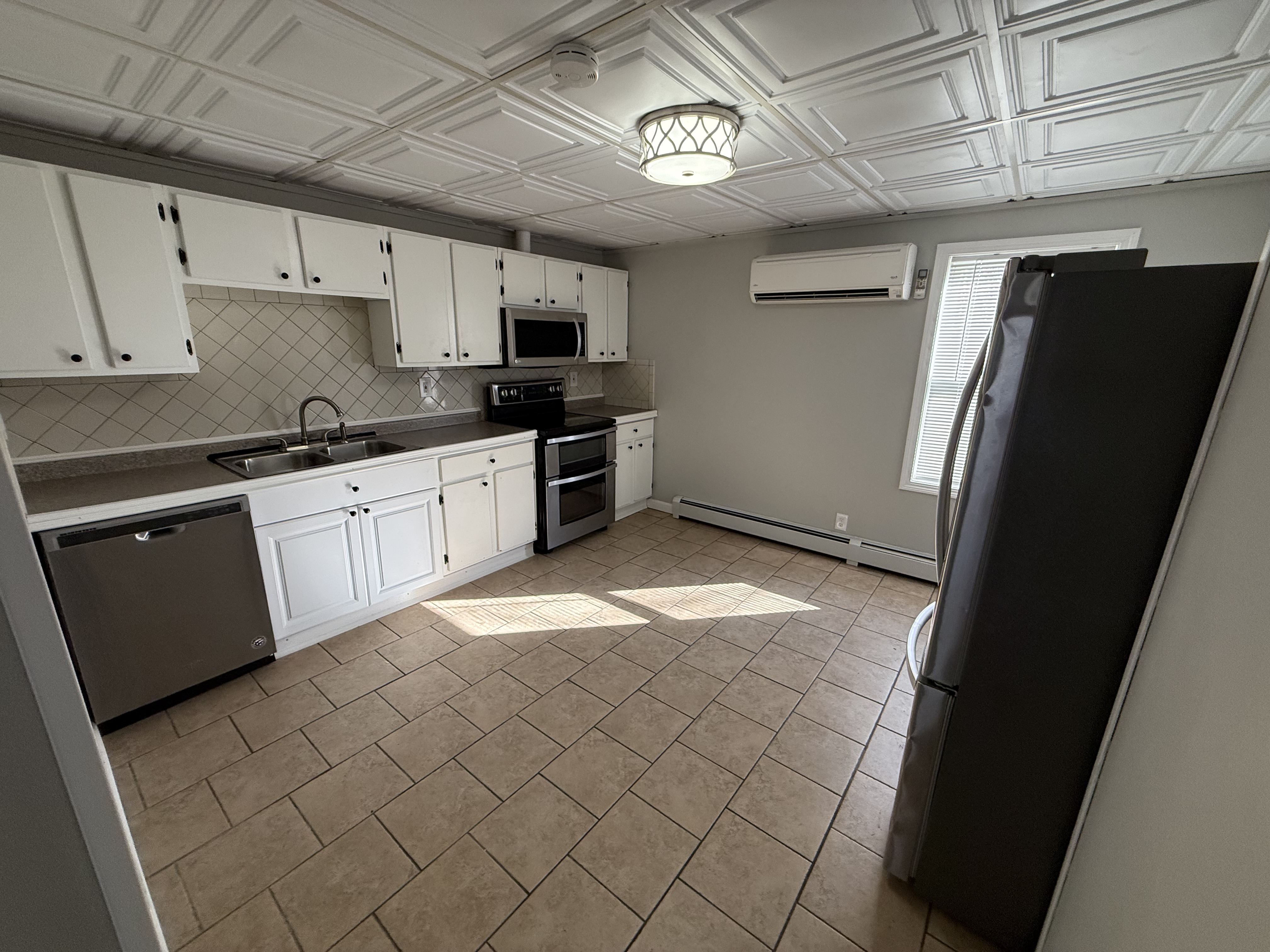 Bright eat-in kitchen with cooling mini-split, white cabinets, and stainless appliances at 41 Donnelly St Apt 2, Fall River MA