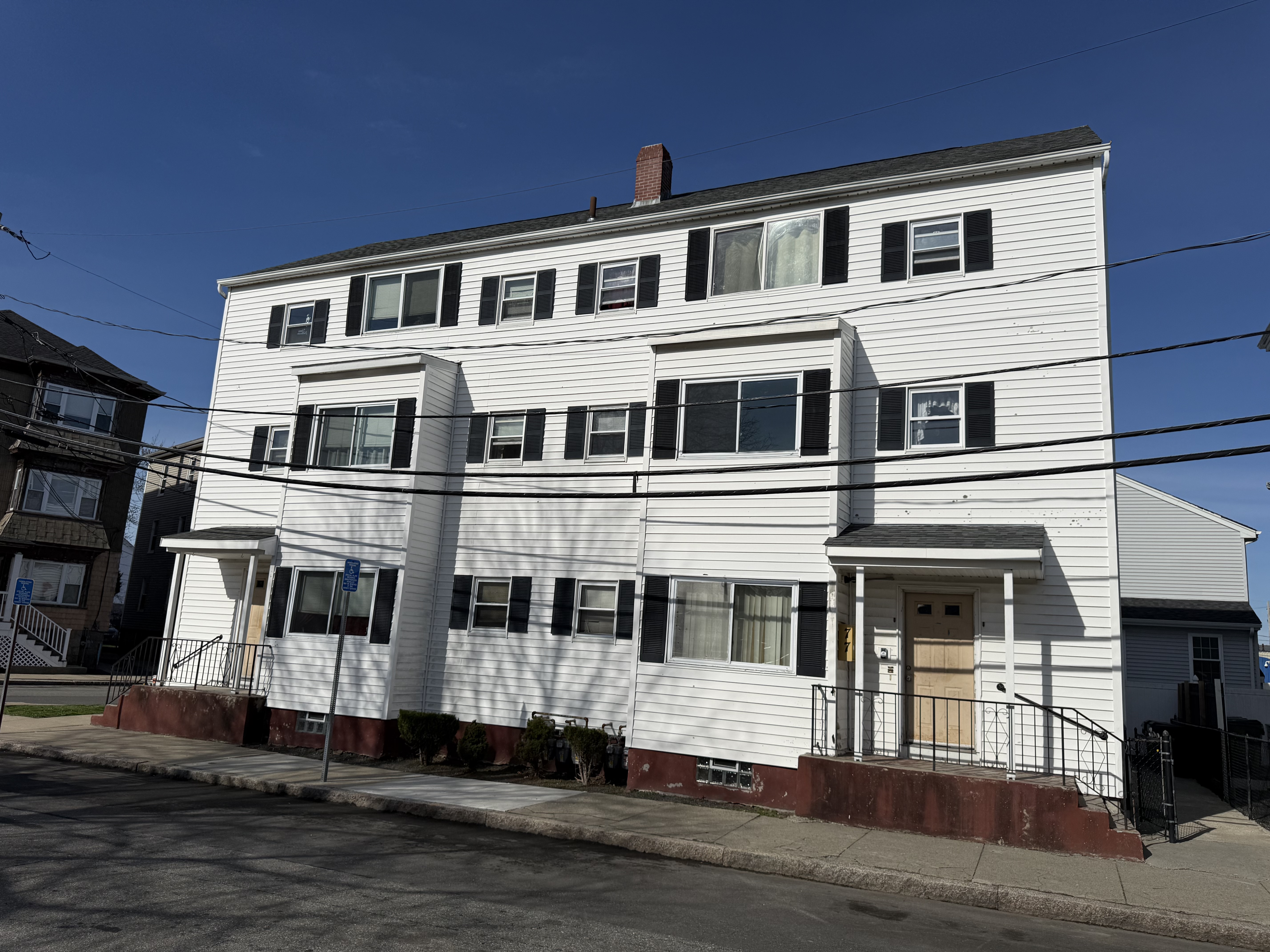 Front view of the white vinyl siding 6-unit building at 77 Massasoit Street