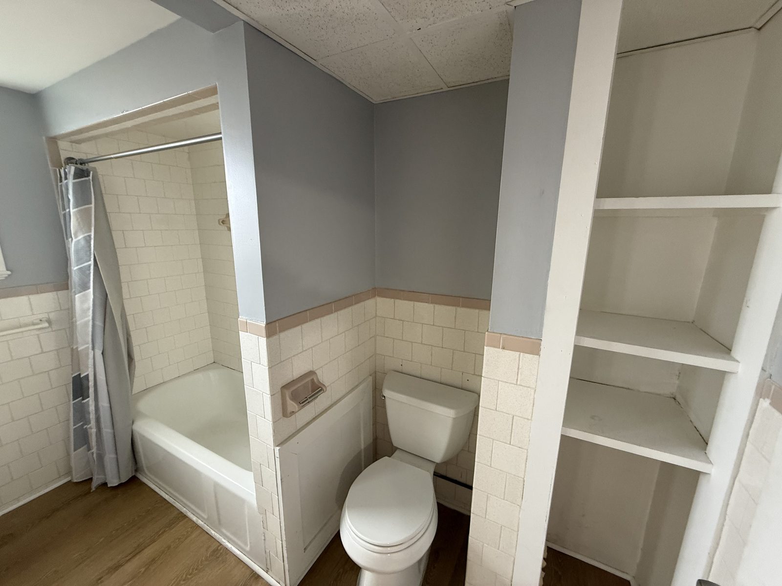 Full bathroom tub and shower in apartment 1N at 795 North Underwood Street Fall River MA with white tile wainscot and built-in shelving