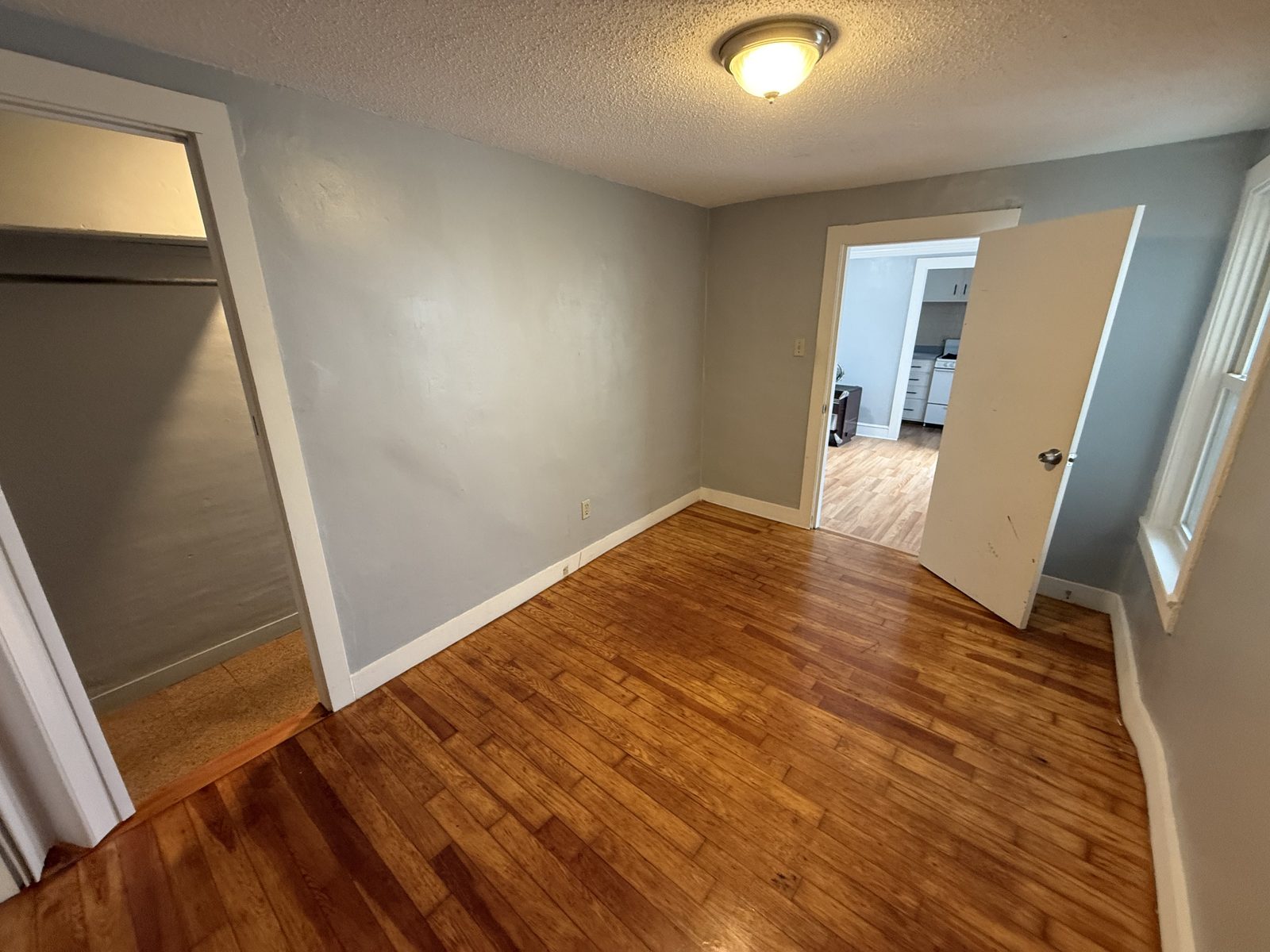 Bedroom 1 angle showing closet, hardwood floor, and doorway to the living room and kitchen in apartment 1N at 795 North Underwood Street Fall River MA