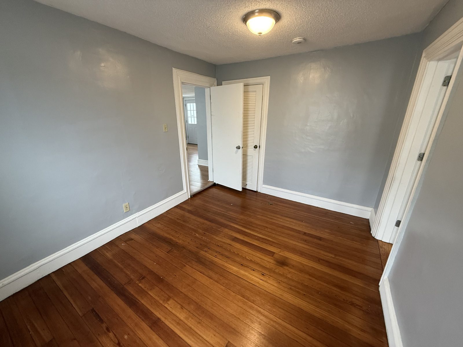 Flex bedroom closet view with hardwood floor and louvered closet door in apartment 1N at 795 North Underwood Street Fall River MA