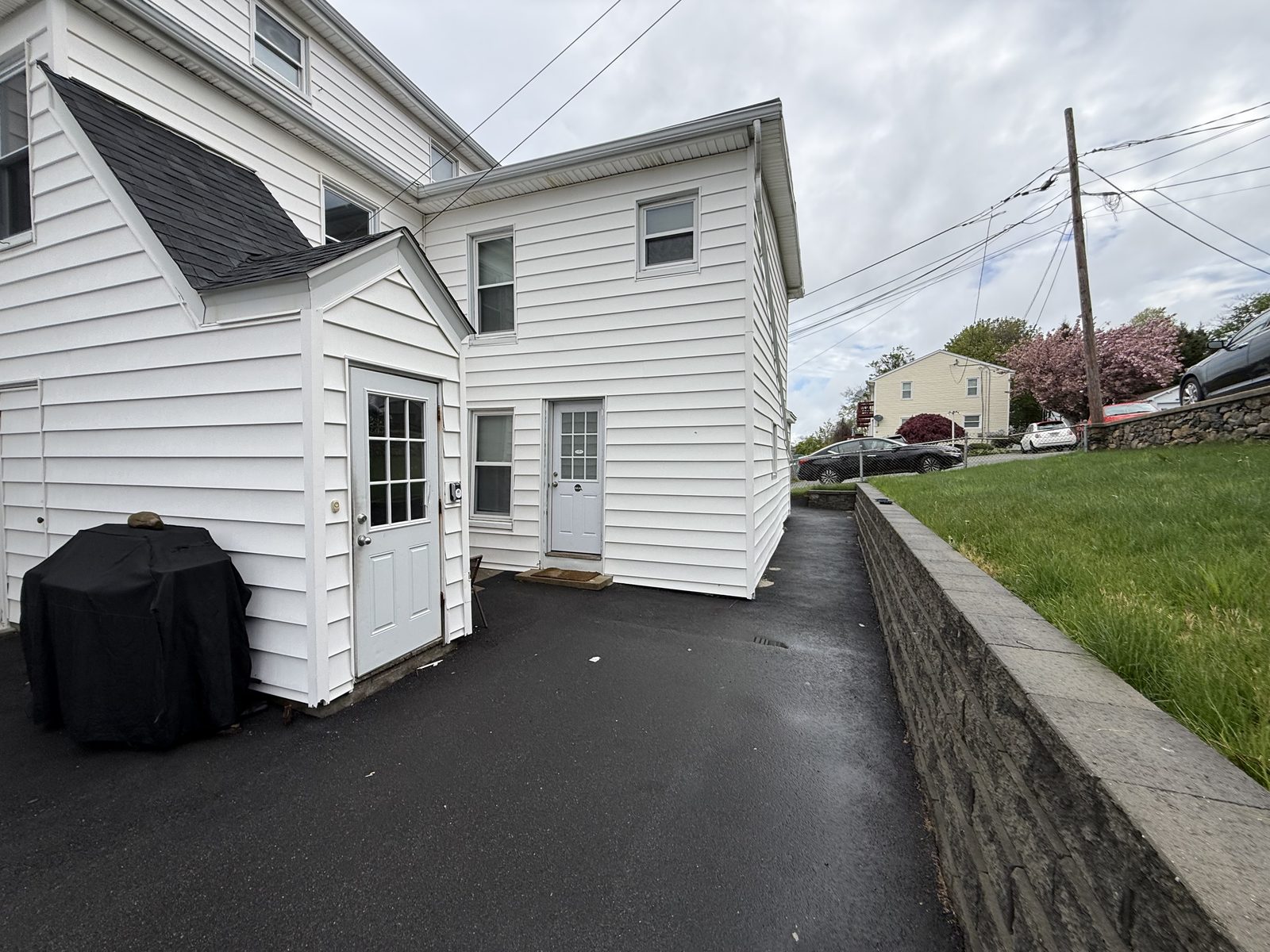 Private back-door entry to apartment 1N at 795 North Underwood Street Fall River MA with paved driveway and retaining wall