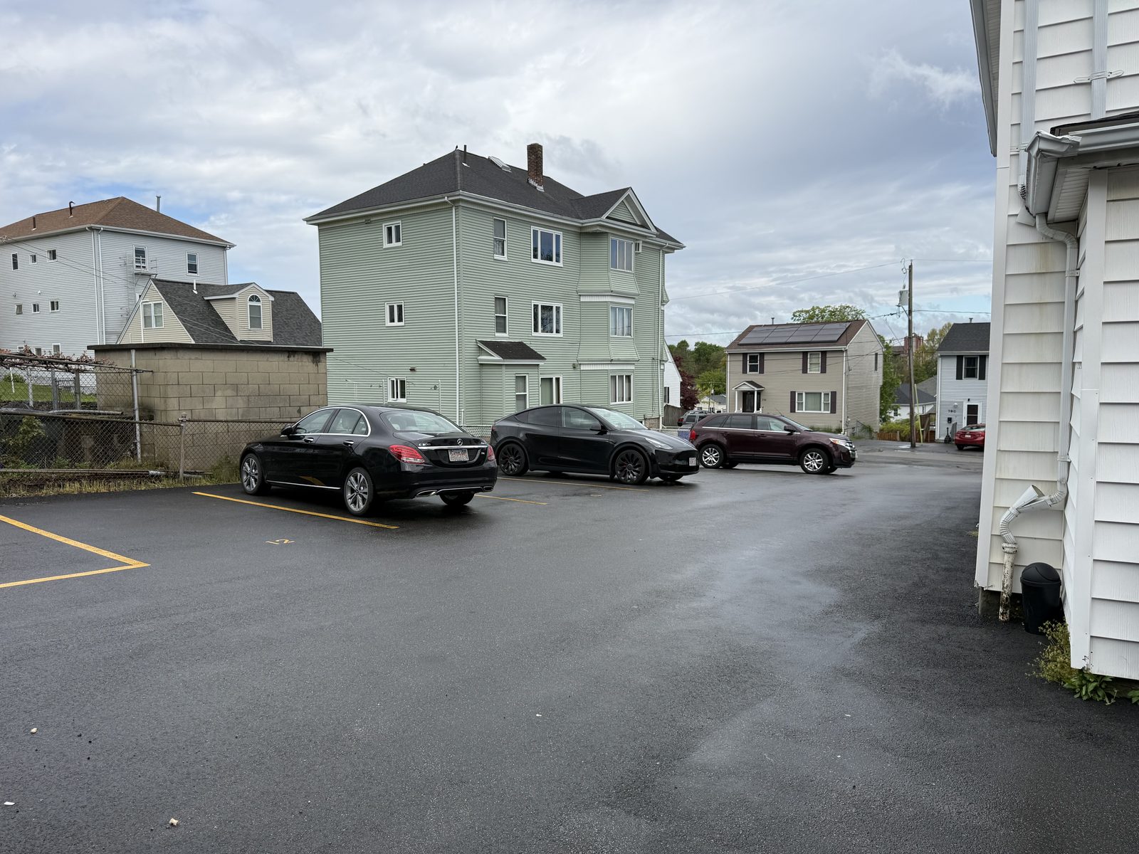 Front exterior of 795 North Underwood Street in Fall River MA — classic white triple-decker with mansard roof and dormers, lawn and parking visible